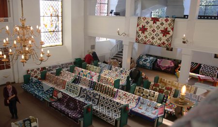 Kirchenbänke bedeckt mit bunten Quilts