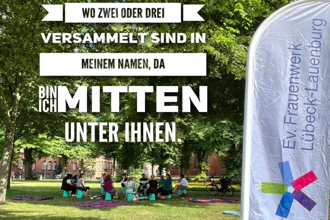 mehrere Personen sitzen im Kreis auf einer Wiese