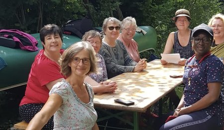 Acht Frauen sitzen am Tisch im Grünen