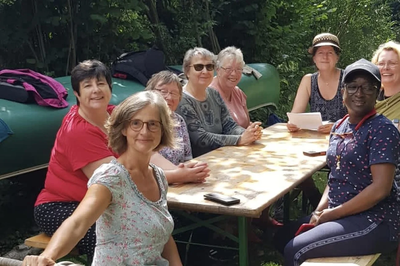 Acht Frauen sitzen am Tisch im Grünen