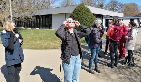 Frauen stehen beieinander, eine schaut in den Himmel