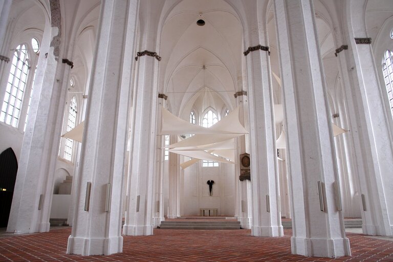 Mehrere weiße Säulen in einer Kirche mit weißen Segeln