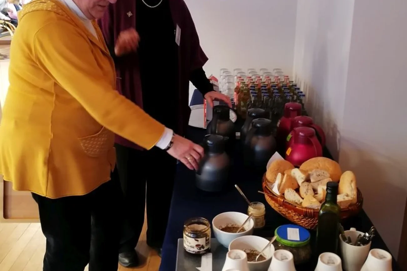 zwei Frauen stehen an einem Tisch mit Tassen und Getränken