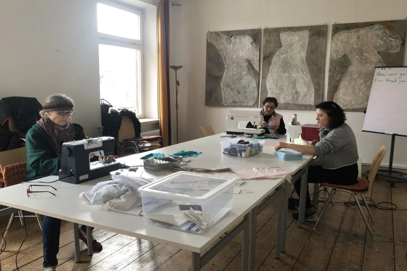 drei Frauen am großen Tisch beim Nähen von Mundschutzmasken