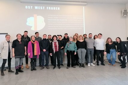 Menschen stehen vor der Präsentation Ost-West-Frauen - Copyright: Ev. Frauenwerk