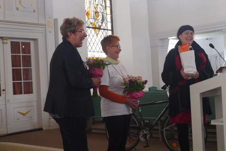 eine Frau übergibt Geschenke an zwei Frauen in der St. Petri Kirche