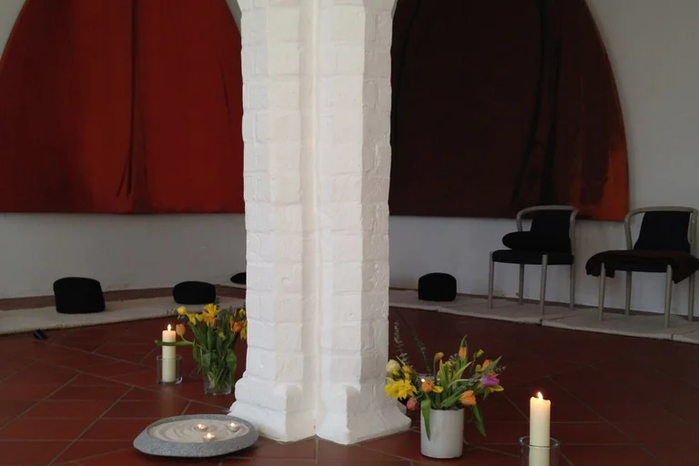 kirchenraum mit stühlen und kissen, kerzen und Blumen